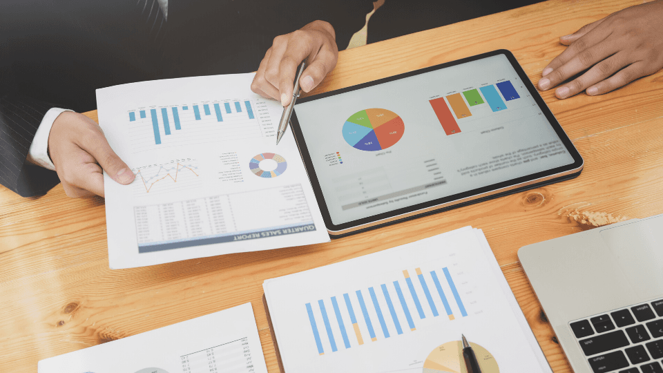 Papers and tablet with graphs on top of a desk