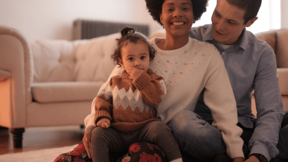 Man, woman and toddler are sitting at the floor with white chair