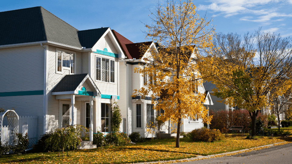 White townhouse with fall trees and yellow leaves on a lawn