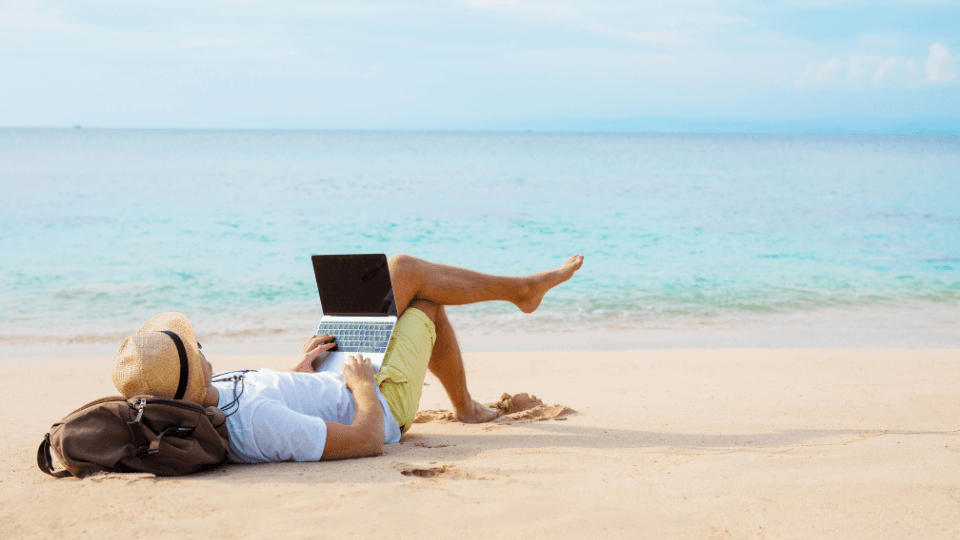 A man With laptop lying on the beach shore
