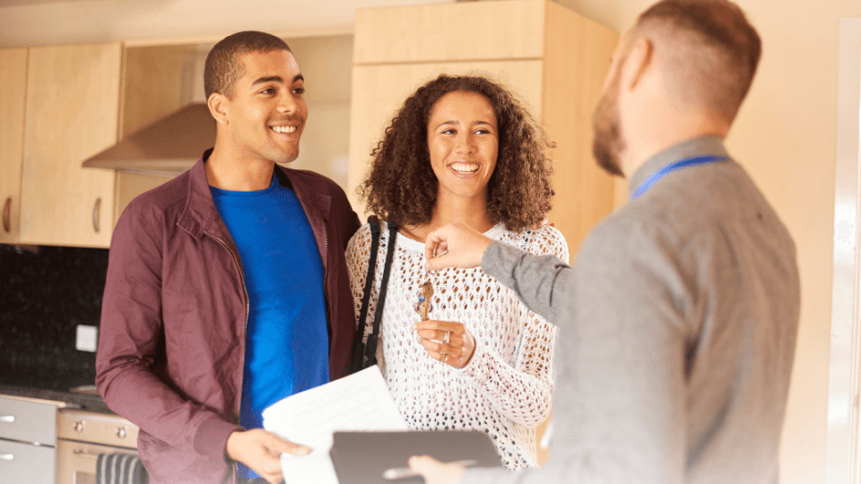 Young Couple taking keys from a realtor in a kitchen